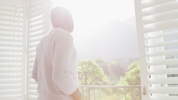 Thoughtful african american senior man looking outside window alt