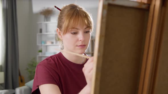 Young Woman Artist Draws a Picture of a House in a Living Room alt