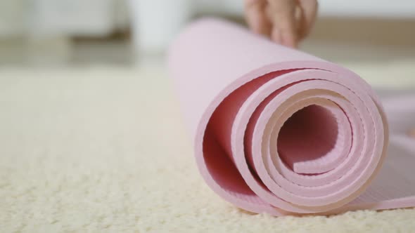 woman rolling fitness yoga pink mat before sports practice for exercise alt