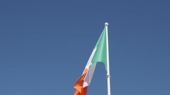 Wavy tricolour striped  Ireland flag against blue sky on wind 4K 2160p 30fps UltraHD footage - Shiny