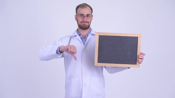 Stressed Bearded Man Doctor Holding Blackboard and Giving Thumbs Down