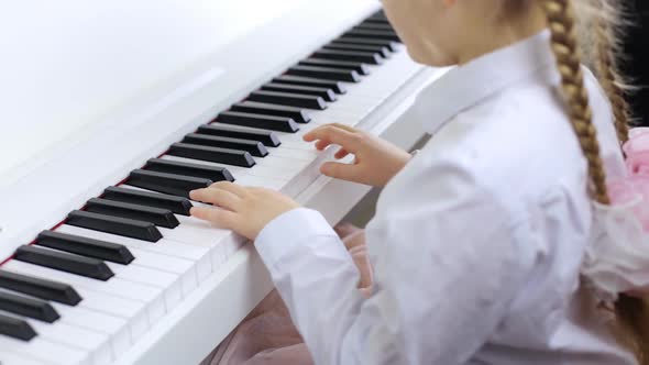 Child Playing Music on a White Piano. The Concept of Playing a Musical Instrument