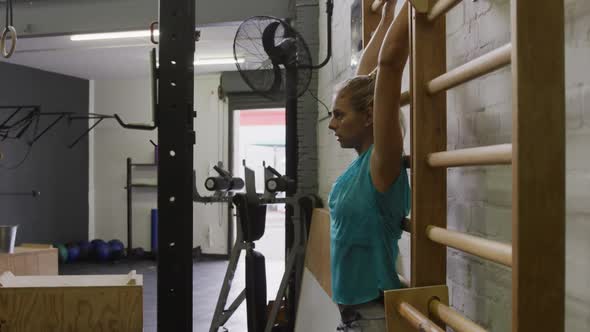 Side view of an athletic Caucasian woman doing leg lifts alt