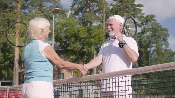 Smiling Mature Couple Shaking Hands After Playing Tennis on the Tennis Court alt