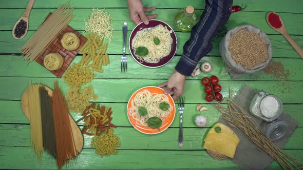 Serving Spaghetti in colorful Plates on green Table for Eating