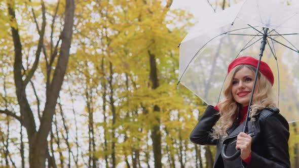 Smiling Happy Cheerful Woman in a Red Suit and a Biker Jacket with a Transparent Umbrella on a Rainy alt