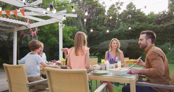 Three generation family enjoying lunch outdoors alt