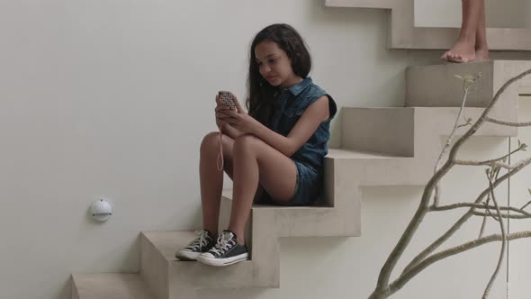 Girl sitting on steps and using mobile phone  mother join her