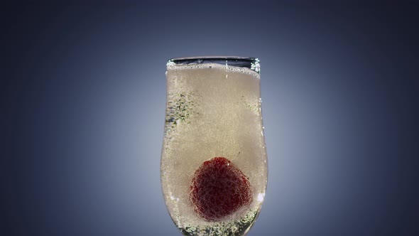 Strawberry Falling Into Full Glass of Champagne Wine. Slow Motion alt