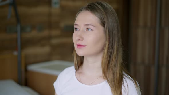 Closeup Portrait of Young Beautiful Slim Woman Looking Out the Window Standing in Hospital Ward alt