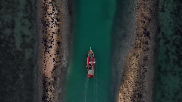 Aerial flight up follow above fisherman boat goes from dock among coral reefs alt
