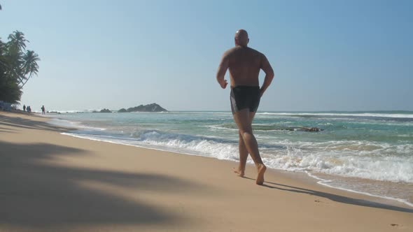 Man Fights with Unhealthy Lifestyle Running Along Shore alt