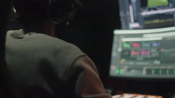 Sound Engineer Seen Seated From Behind Uses the Computer to Mix Audio Music alt
