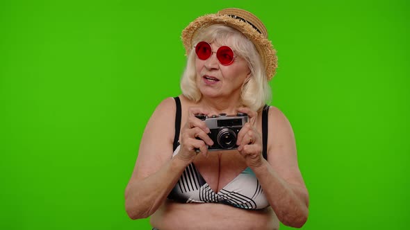 Senior Woman Tourist Photographer Taking Photos on Retro Camera and Smiling on Chroma Key Background alt
