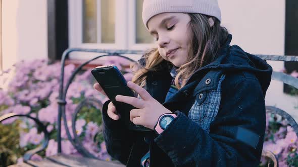 Young Child Girl Plays or Watchs Video on Smartphone