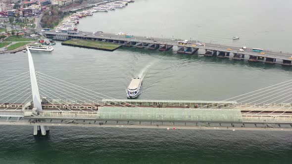 Aerial drone top down view as a ferry crosses under Halic Metro Bridge on the Bosphorus River on a c alt