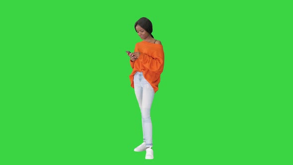 A Beautiful Young Woman Using Her Phone on a Green Screen, Chroma Key. alt
