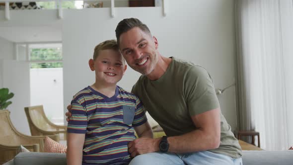 Portrait of caucasian father and son smiling in the living room at home alt