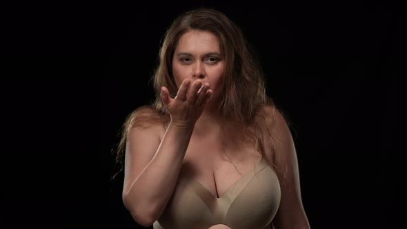 Seductive Plus Size Woman Gesturing Air Kiss Looking at Camera Posing at Black Background alt