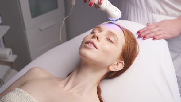 in a Modern Spa, a Cosmetologist Performs a Hardware Lift on a Woman's Face alt