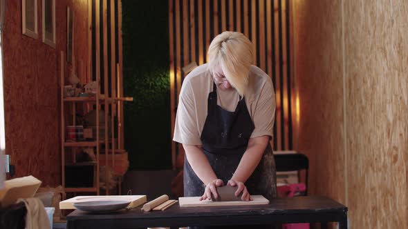 An Elderly Woman with Short Hair Kneading a Piece of Clay alt