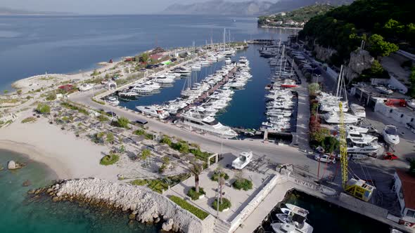 Aerial Flight Above the Marina with Yachts in the Sea Bay Near the Mountains