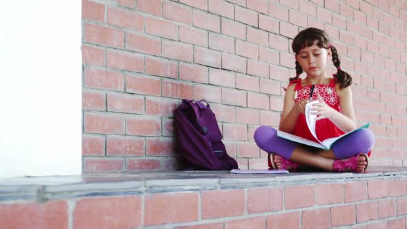 School girl sitting in corridor and doing homework at school alt