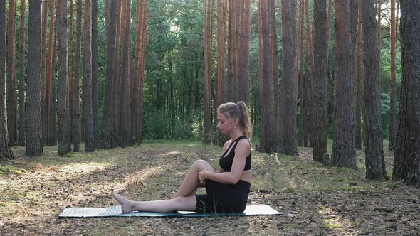 Young Caucasian Woman Sitting in Wise Man Pose Called Marichyasana at Forest