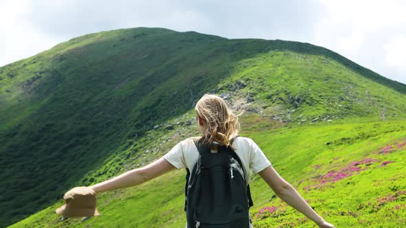 Successful Girl Hiker with Backpack Relaxing on the Top of the Mountain and Enjoying the View of the