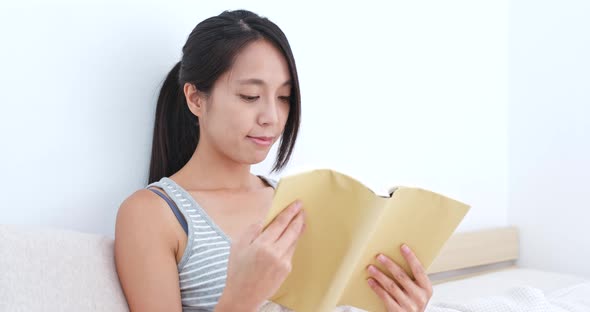 Woman reading book on bed alt