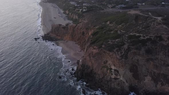 AERIAL: Flight Over Malibu, California View of Beach Shore Line Pacific Ocean at Sunset with alt