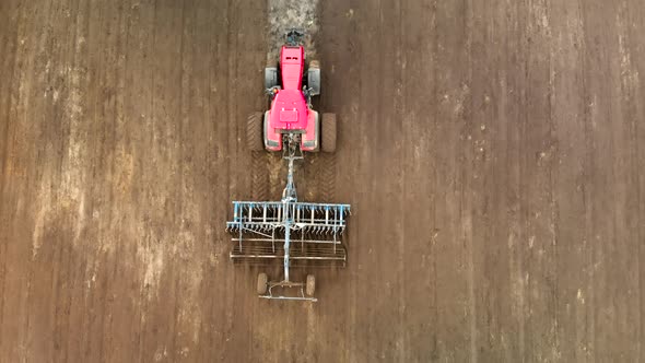 Flying Over a Modern Tractor with a Disc Harrow Cultivating Heavy Soil in Spring alt