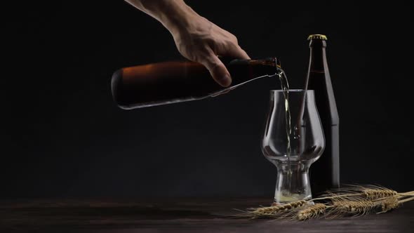 Male Hand Pours Beer Into a Glass on the Table