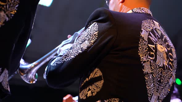 Panning up from shoes, focus on Mariachi costume, charro, of trumpet player. alt