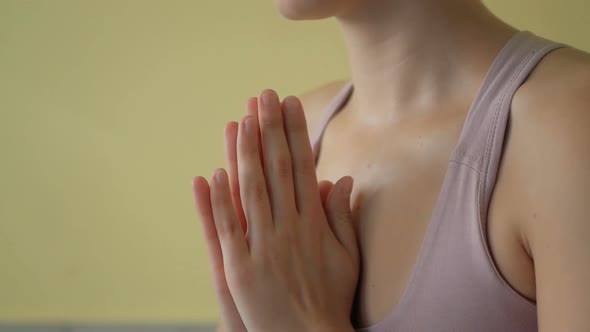 Close-up of hands of sporty young beautiful woman meditating indoors, focus on arms in Namaste gestu