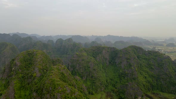 Aerial Shot of Beautiful Limestone Mountains with Passes Carved By a River in Ninh Binh Region a alt