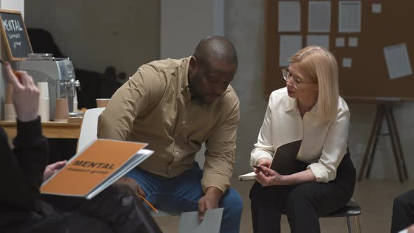Female Psychologist Talking to Black Man during Group Session alt