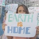 Portrait of Woman Holding Earth Is Home Poster and Looking at Camera. Female Protester Standing - VideoHive Item for Sale