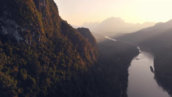 Aerial: flying over Nam Ou River Nong Khiaw Muang Ngoi Laos, sunset dramatic sky alt