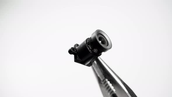 Hidden Camera Module Closeup in Pliers on a White Background alt