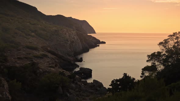 Exploring rocky mountain cliffs, cove beach at golden hour sunset, dolly alt