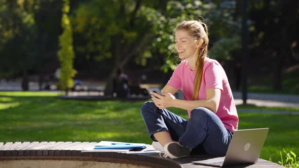Cheerful Woman Browsing Internet on Smartphone Outside