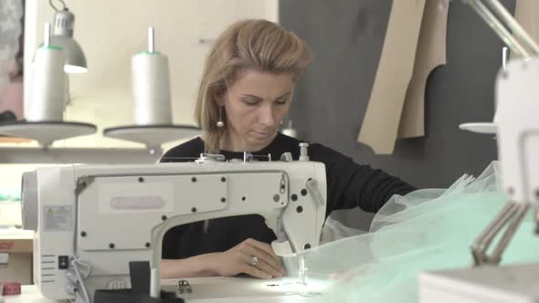 Blonde Beautiful Caucasian Female Sitting at Table with Sewing Machine in Classroom Working in alt