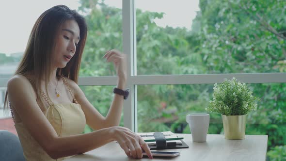 Mobile payment concept : Young beautiful Asian woman enjoying a relaxing moment working and using mo alt