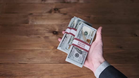 Male Hands Hold Three Stacks of 10000 US Dollar Bills and Show Thumb Up Sign alt