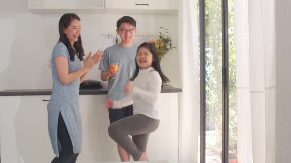 Happy young Asian family listen to music and dancing after breakfast at home. alt