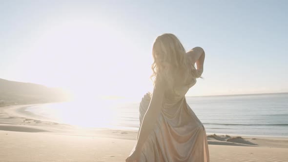 Young Dancing Woman In Gold On Beach alt