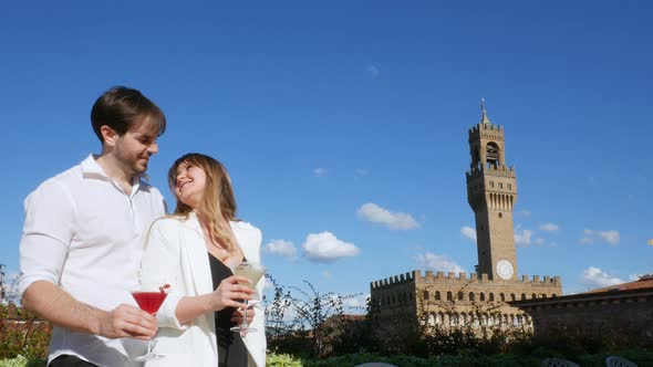 Young couple holding cocktails and kissing, Florence, Tuscany, Italy