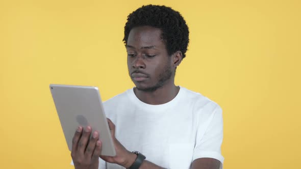 African Man Excited for Success While Using Tablet Yellow Background alt