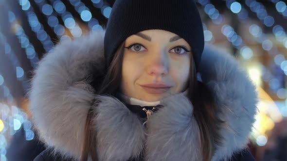 Beautiful Young Woman Standing on Decorated Street with Garland Lights on Celebrating Christmas and alt